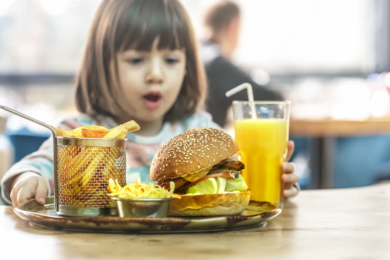 niña comiendo un menu infantil - hamburguesa más patatas fritas